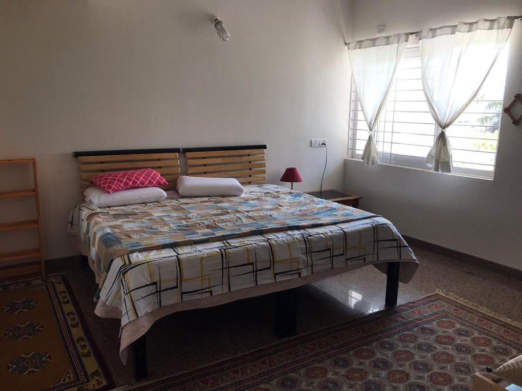 a bedroom with a bed in a room with a window at shavāsanā homestay in Vānivilāsa Puram