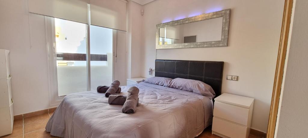 ein Schlafzimmer mit einem großen Bett und einem Spiegel darauf in der Unterkunft Homes of Spain, Atico Lomas del Mar V con vistas al mar y solárium grande, WIFI in Playas de Vera