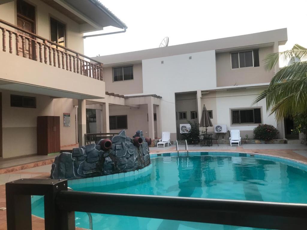 a swimming pool in front of a building at Neradom Hotel in Tema