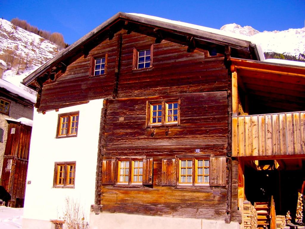 a wooden house with a balcony in the snow at Haus Nicca in Splügen