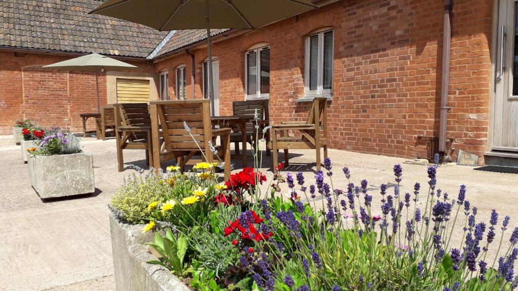 un giardino con fiori e tavoli e un ombrellone di Courtbrook Farm Apartments a Exeter