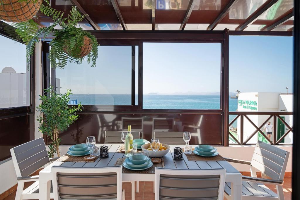 een eetkamer met een tafel, stoelen en ramen bij Apartamentos La Estrella iii in Playa Blanca