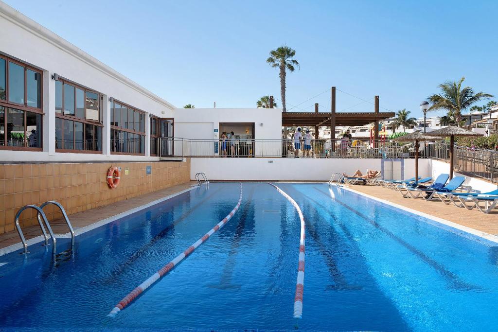 une piscine à l'eau bleue dans un complexe hôtelier dans l'établissement Playa Flamingo 34, à Playa Blanca