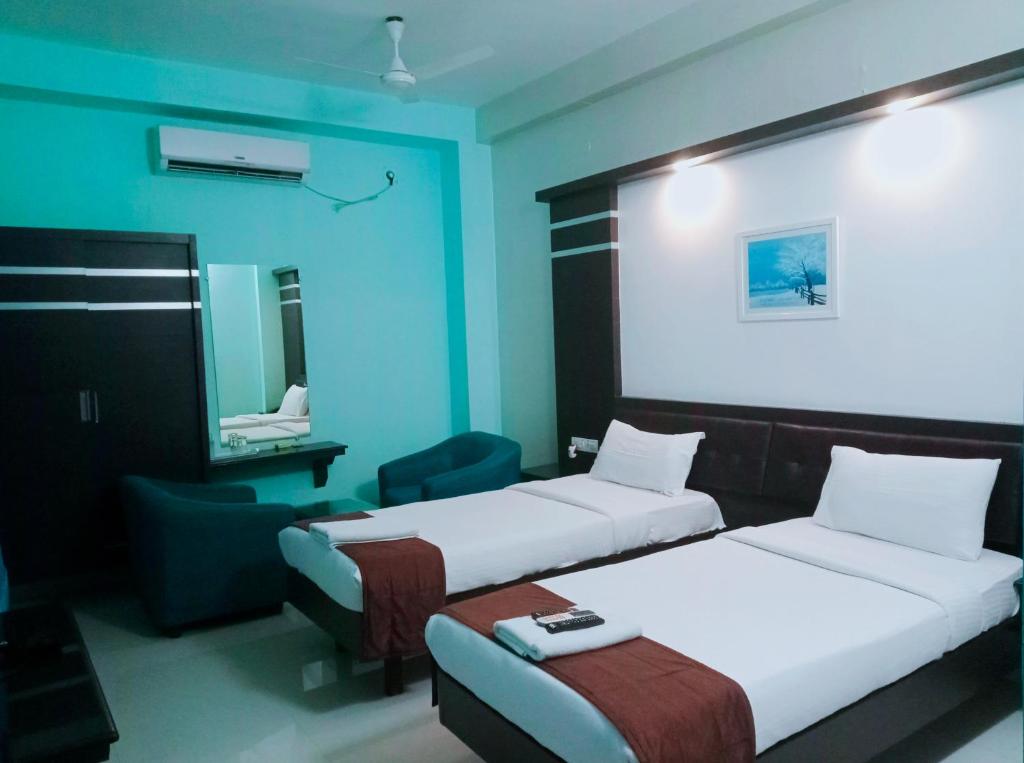 een kamer met 2 bedden, een stoel en een spiegel bij Pine Tree in Kanchipuram