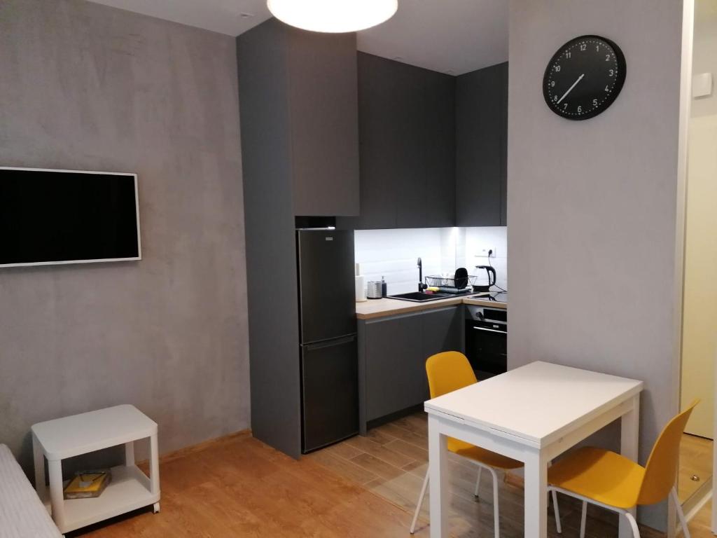 een kleine keuken met een witte tafel en gele stoelen bij Apartament Zet in Nałęczów