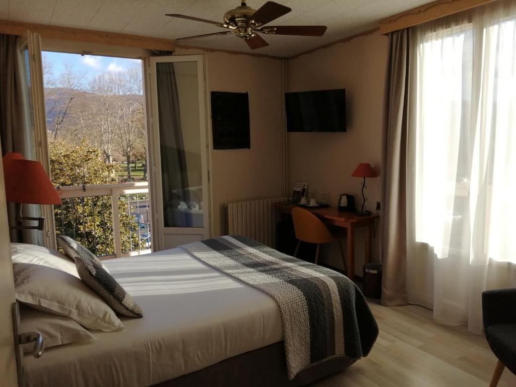 a bedroom with a bed and a window and a desk at Hôtel L&#39;Iroko The Originals City in Aix-les-Bains
