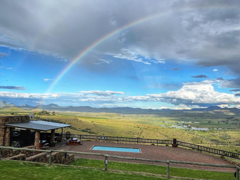 a rainbow over a house with a pool at Uitzicht Private Nature Reserve and Lodge in Fouriesburg