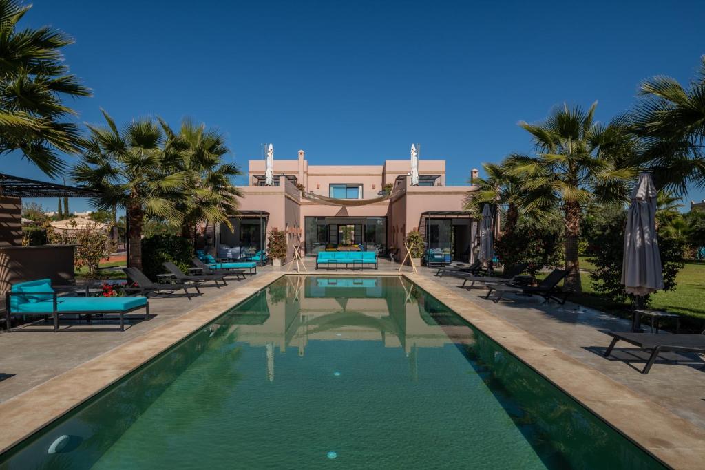 ein Pool vor einem Haus mit Palmen in der Unterkunft Les Iris - Peaceful villa with heated private pool & hammam in Marrakesch