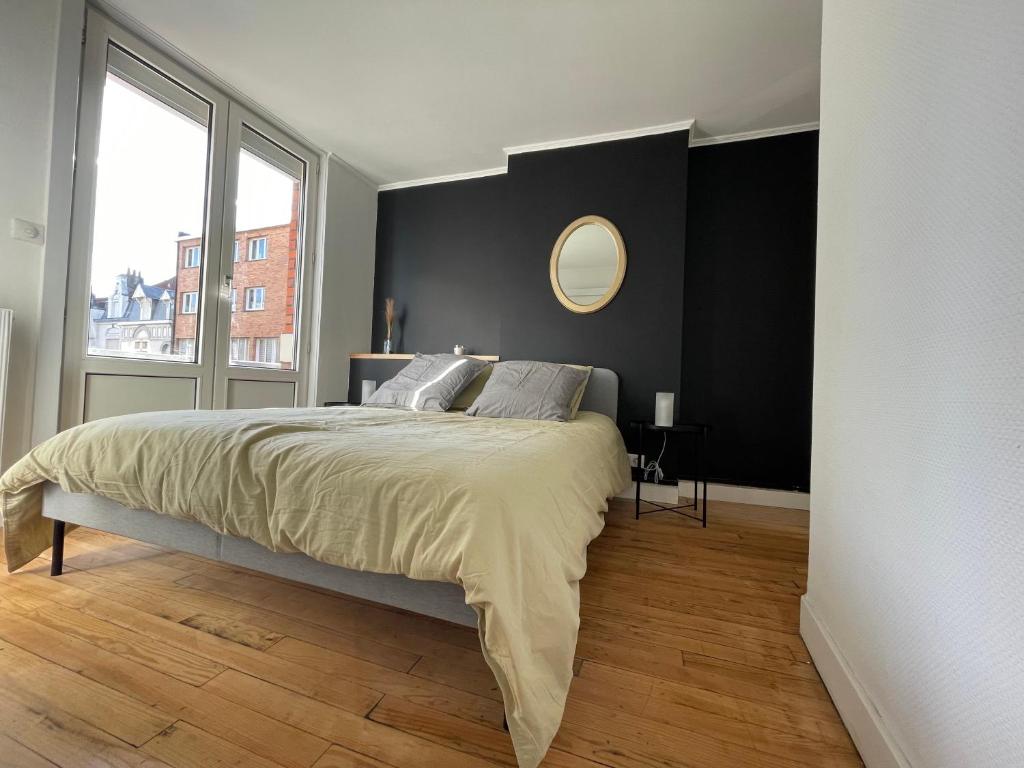 une chambre avec un grand lit avec un miroir au mur dans l'établissement Appartement Malouin - Villa Leopold, à Dunkerque