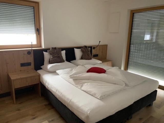 a large bed with white sheets and pillows in a bedroom at Dependance Residence Altea in Ortisei