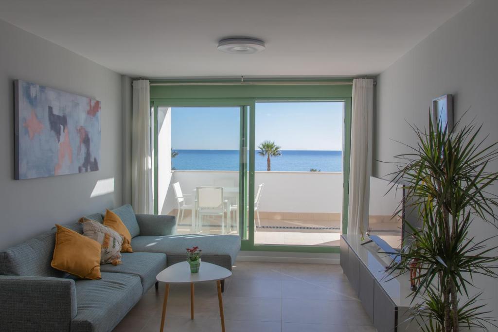 uma sala de estar com um sofá e vista para o oceano em Precioso apartamento frente a la playa con piscina em Mojácar