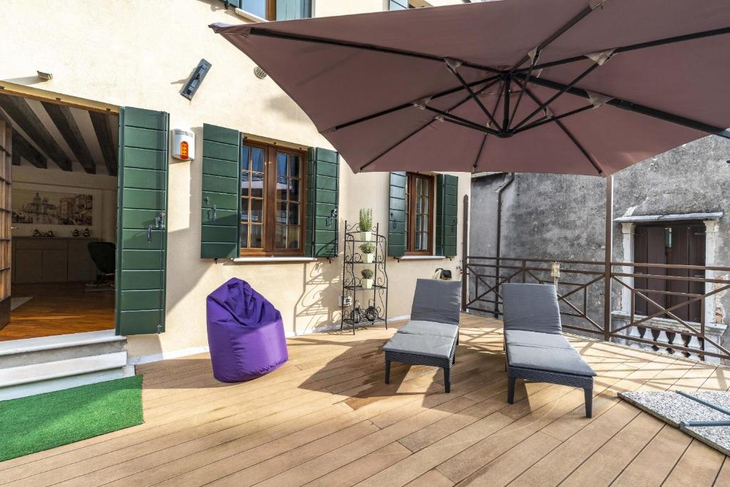 een terras met 2 stoelen en een parasol bij TOLENTINI Canal View & Terrace in Venetië
