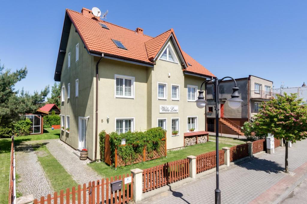 a yellow house with a red roof on a street at Willa Linc Łeba in Łeba