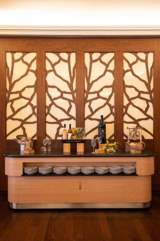 A compact wooden drinks and tableware station is styled against a decorative wall.