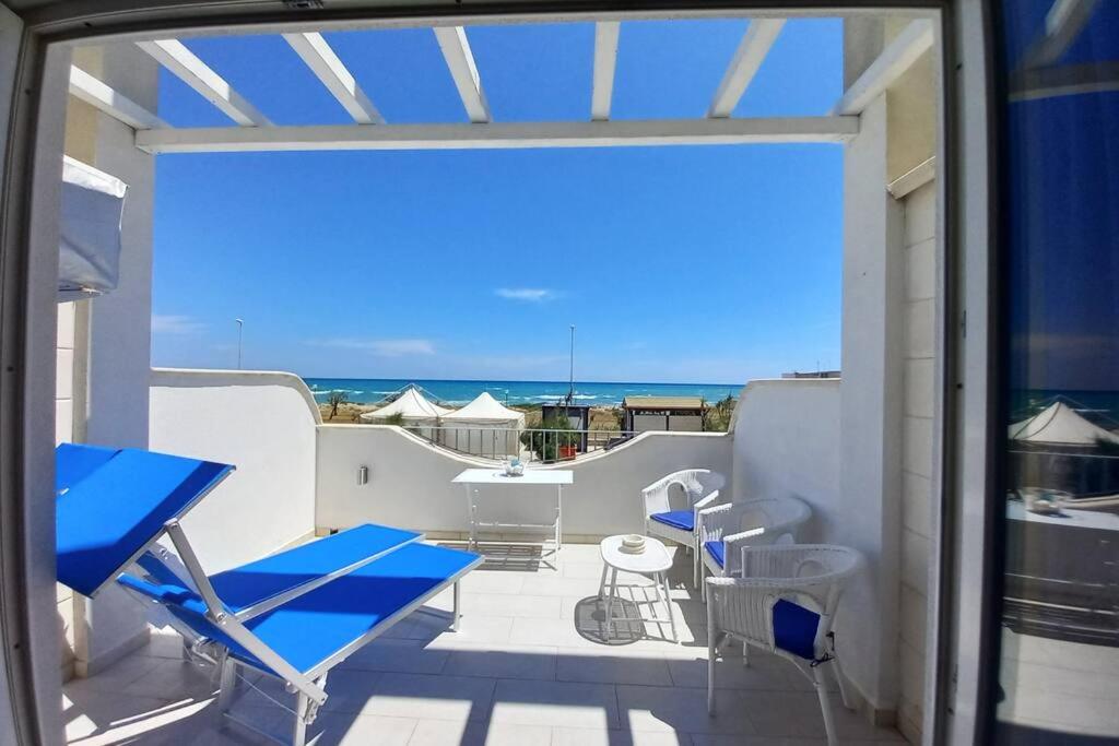 balcone con sedie blu e vista sull'oceano di Oblò sul Mare - Villa nel cuore del Salento a Lendinuso