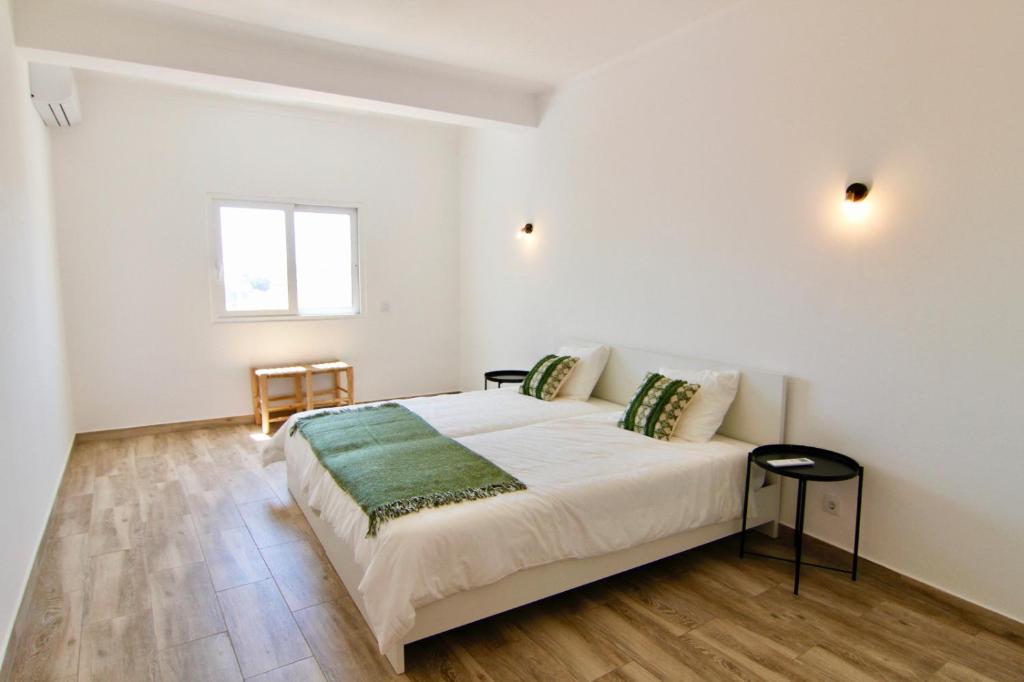 ein weißes Schlafzimmer mit einem Bett und einem Fenster in der Unterkunft Lagoa Central by Homing in Lagoa