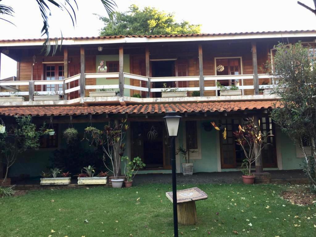 una casa con balcón y un banco en el patio en Confortável Casa de Campo em Condomínio Fechado, en Águas de Lindóia