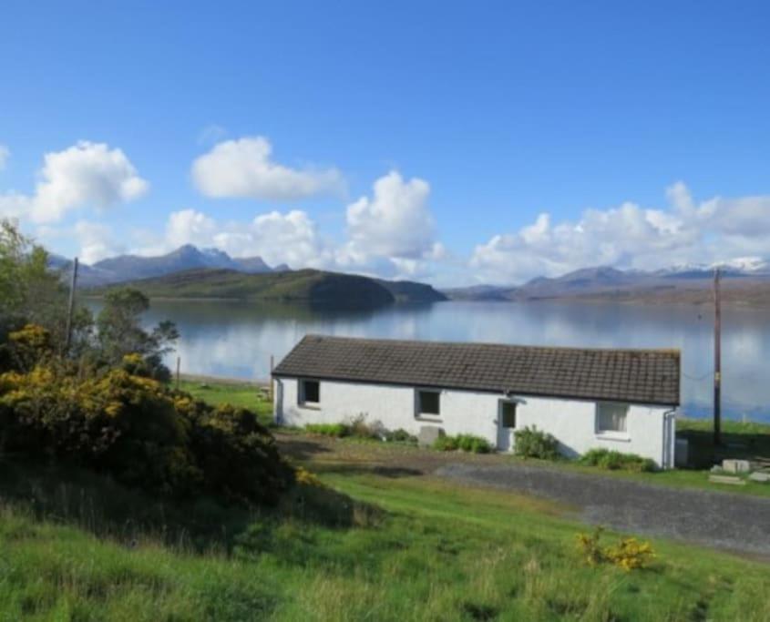 a white house with a lake in the background at Spectacular Highland Cottage Overlooking the Sea in Tongue