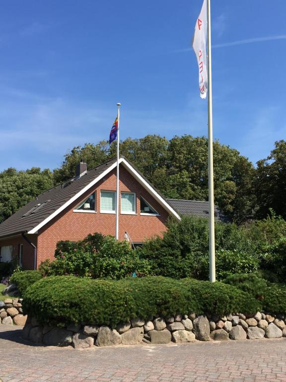 une maison avec deux drapeaux devant elle dans l'établissement Haus Burmeister, à Tinnum
