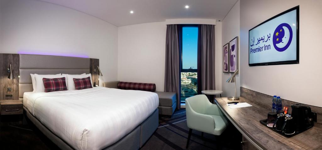 a hotel room with a bed and a desk at Premier Inn Dubai Barsha Heights in Dubai
