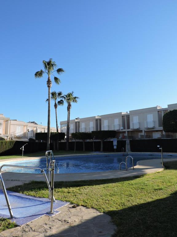 una piscina con palmeras en el fondo en APARTAMENTO DÚPLEX VERA-GARRUCHA, en Garrucha