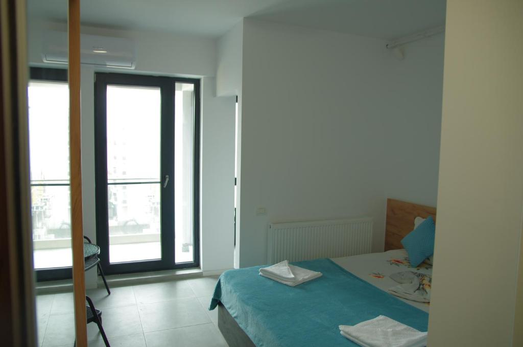 een slaapkamer met een bed met blauwe lakens en een raam bij Studio David Eforie Nord in Eforie Nord