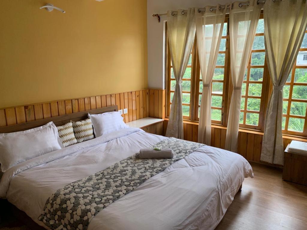 ein großes Bett in einem Schlafzimmer mit Fenstern in der Unterkunft NOLINA BOUTIQUE HOMESTAY in Namchi