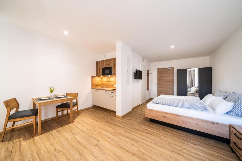 a bedroom with a bed and a desk and a kitchen at Kaneder Hof - Self Check-in in Inchenhofen