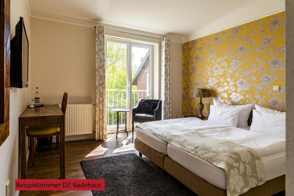 a bedroom with a bed and a desk and a window at Hotel & Restaurant Villa Ulmenhof in Bredstedt