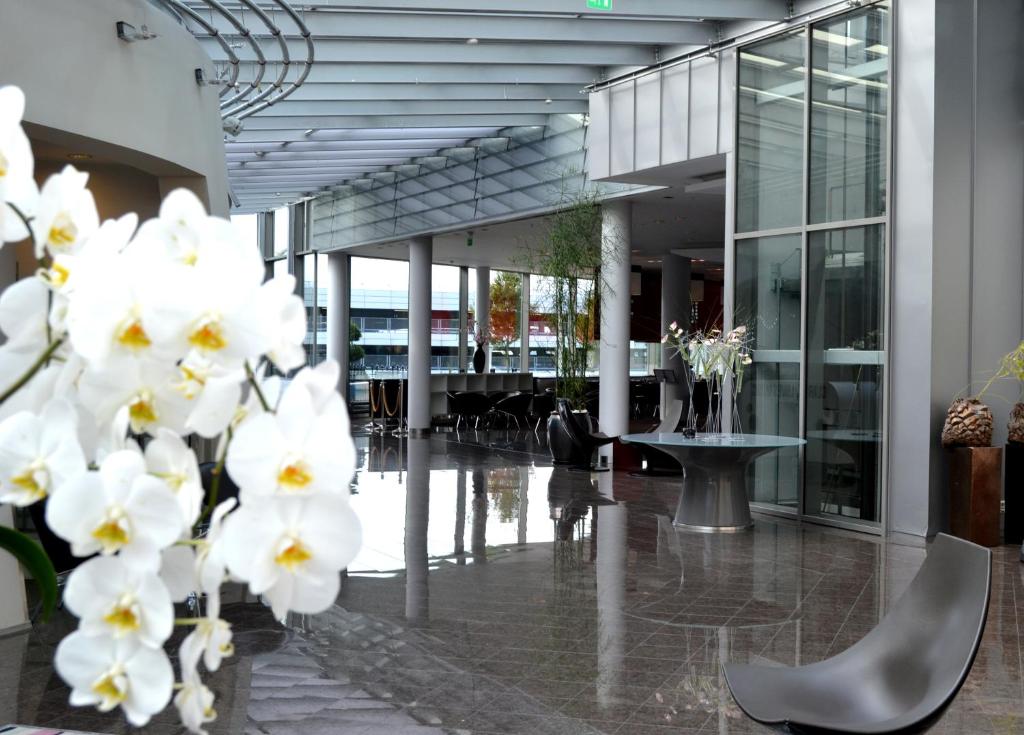 a lobby of a building with white flowers in the foreground at Clarion Hotel Bergen Airport in Bergen