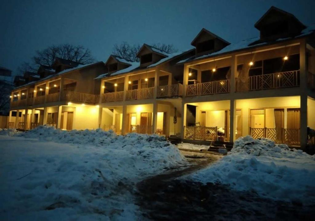 a building with snow in front of it at night at Woodridge Cottages Kalam in Kalām