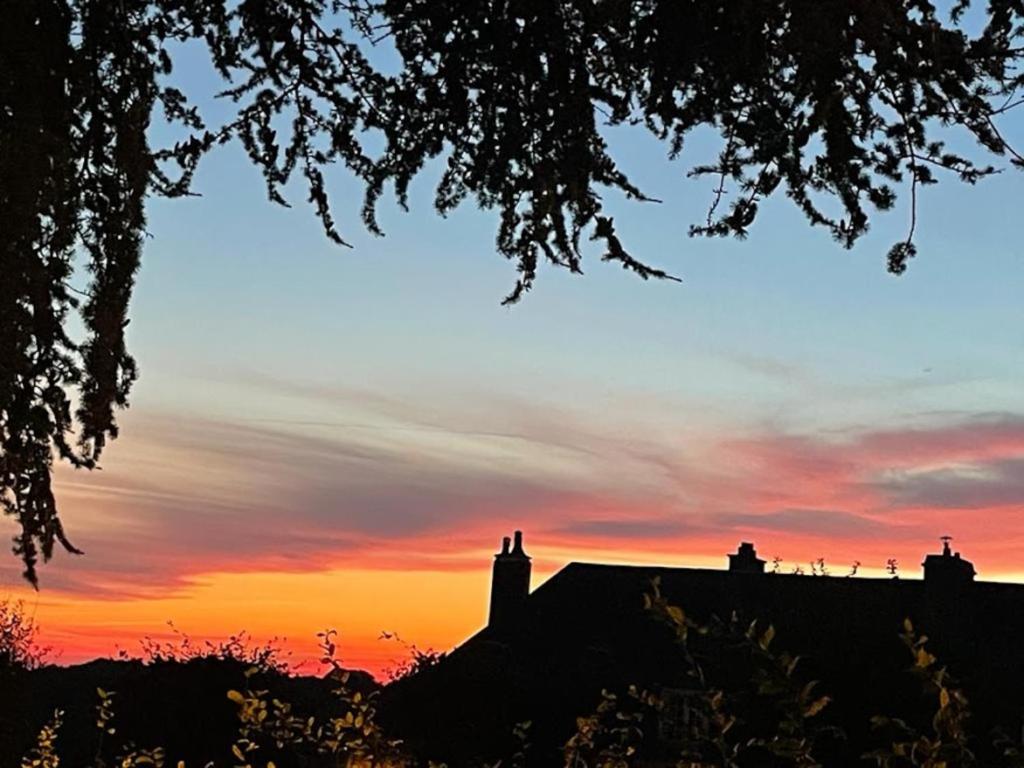 a sunset over a house with a roof at La tour cachée in Mortain