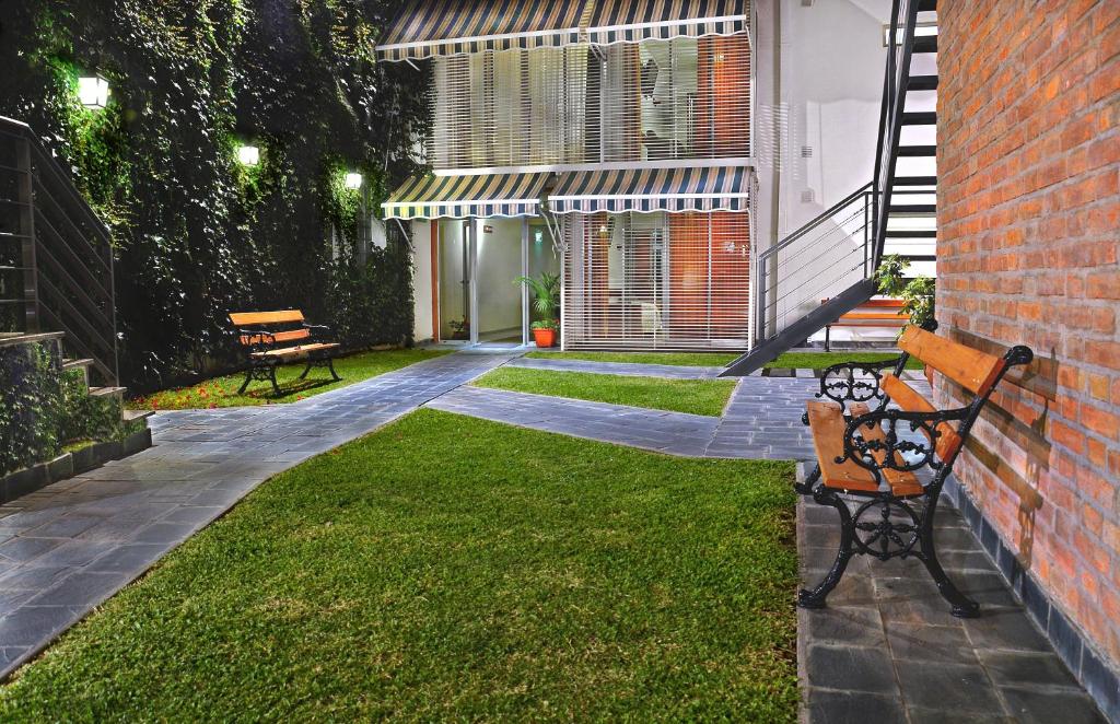 two benches sitting on the grass in a yard at Nuna Ayni Apartments in Alta Gracia