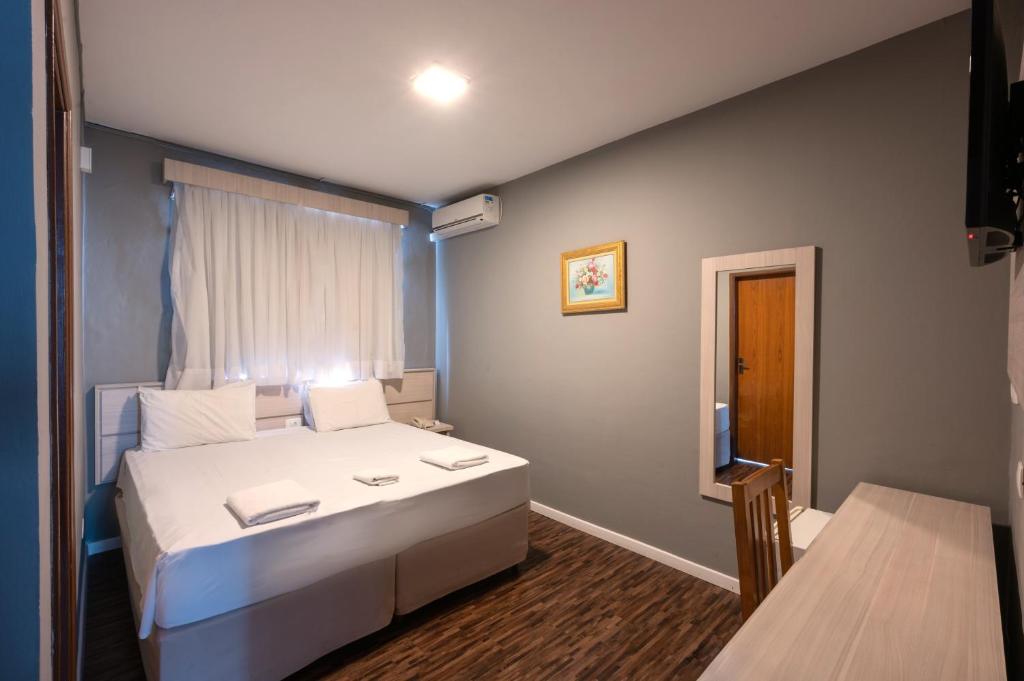 ein Schlafzimmer mit einem großen weißen Bett und einem Fenster in der Unterkunft Italian Palace Hotel Rede Carlton in Três Corações