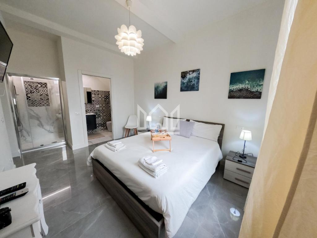 sypialnia z dużym białym łóżkiem i żyrandolem w obiekcie Gold River House w mieście Ferrara