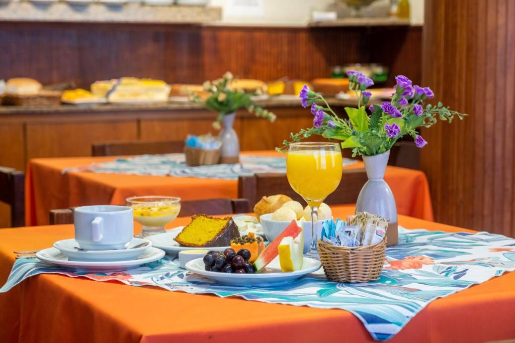 a table with orange clothed tables with food and drinks at Hotel Mount Everest in Nova Friburgo