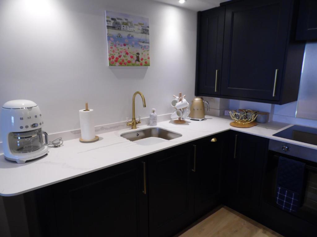 eine Küche mit schwarzen Schränken und einer Spüle in der Unterkunft Beachside Apartment in Carbis Bay
