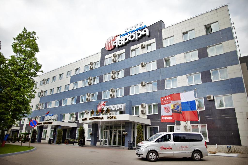 ein weißes Auto, das vor einem Gebäude parkt in der Unterkunft Avrora Business Hotel in Kursk