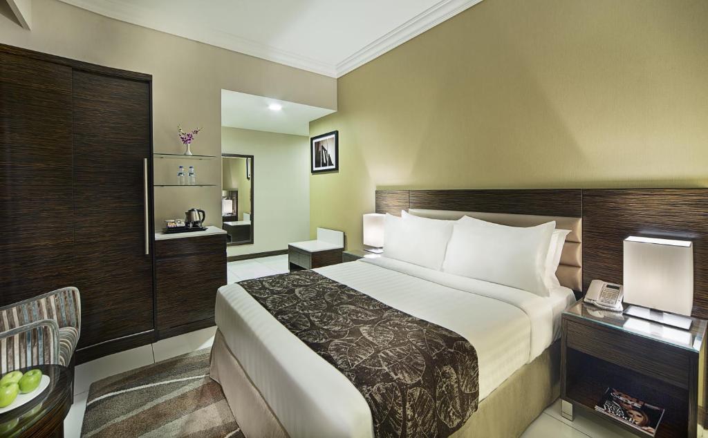 a hotel room with a large bed and a chair at Gateway Hotel in Dubai
