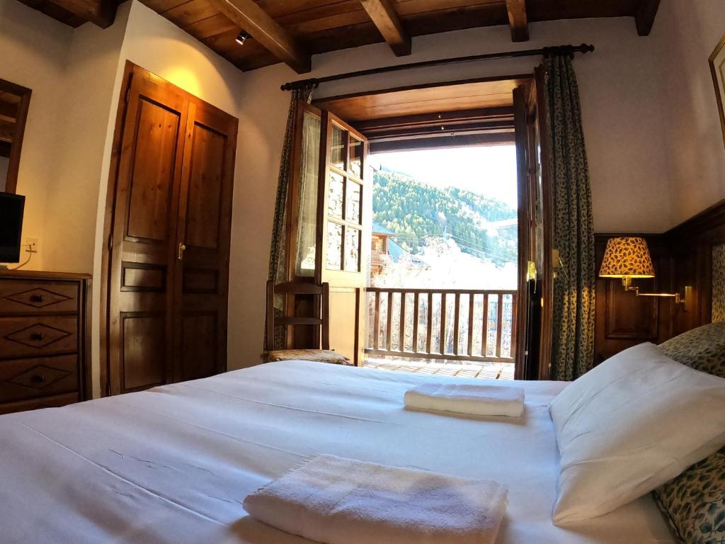 um quarto com uma cama grande e uma janela grande em AC Apartaments Tarter Chalet em El Tarter