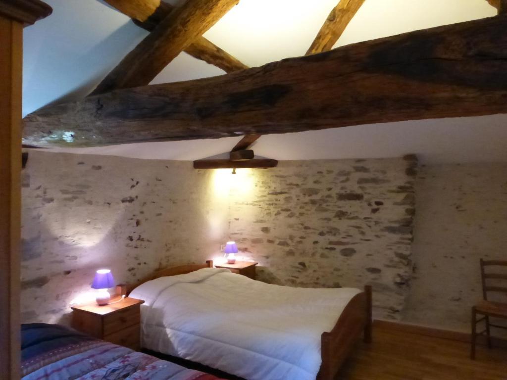 une chambre avec deux lits et un mur en pierre dans l'établissement Domaine de la Garneraie, à Le Champ-Saint-Père