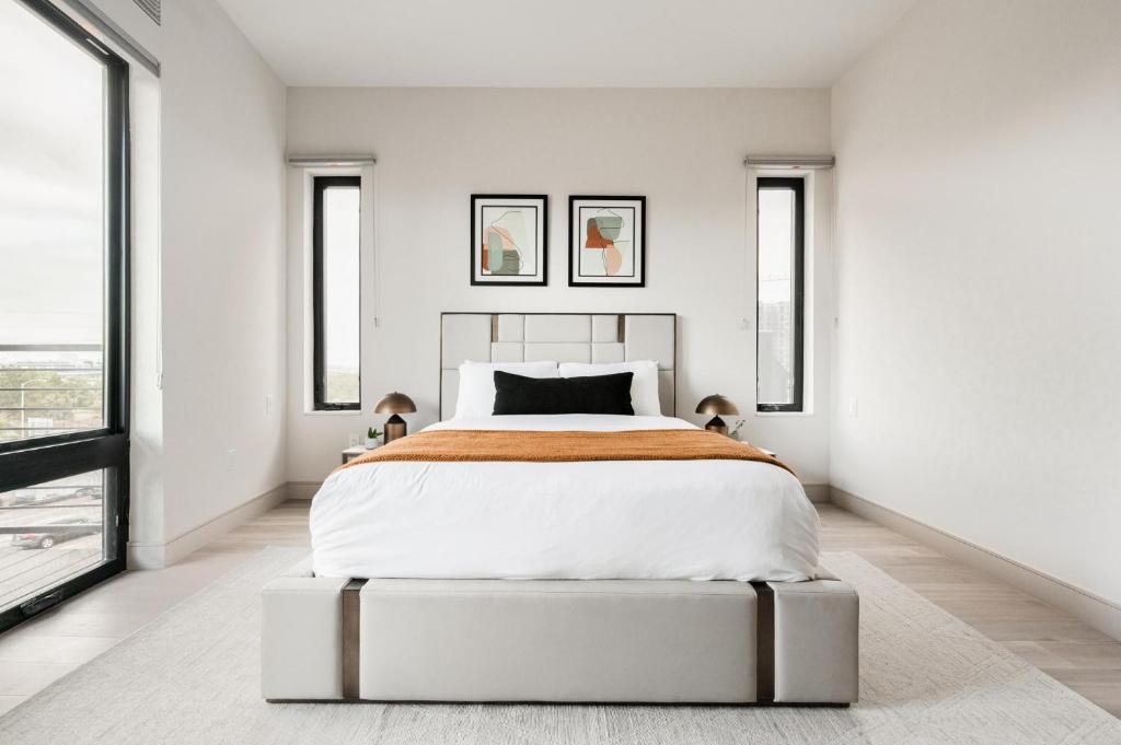 a bedroom with a large bed with white walls and windows at City Views! - Chic Jefferson Park Condo - Tesoro in Denver