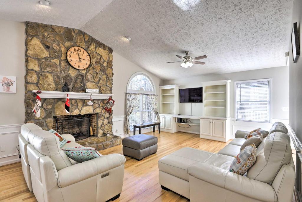 a living room with two couches and a stone fireplace at Immaculate Suwanee House with Pool and Game Room! in Suwanee