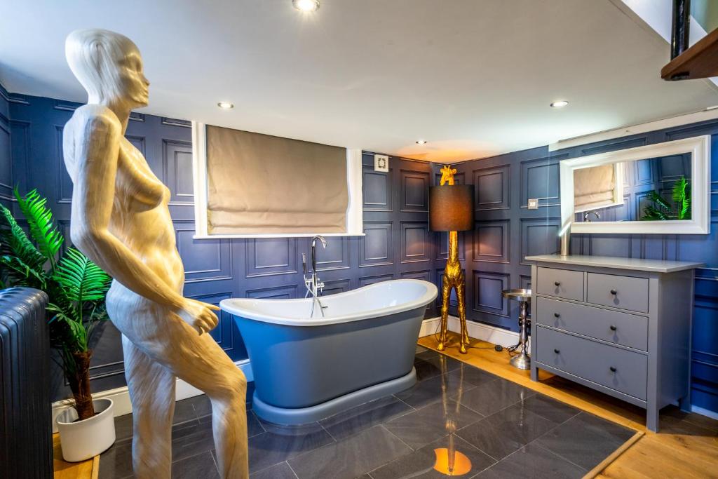 un baño con una estatua de un hombre de pie junto a una bañera en The School House, en York