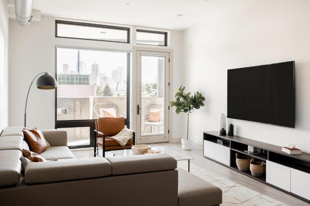 a living room with a couch and a flat screen tv at Brand New Condo - Walk to Empower Stadium - Tesoro in Denver