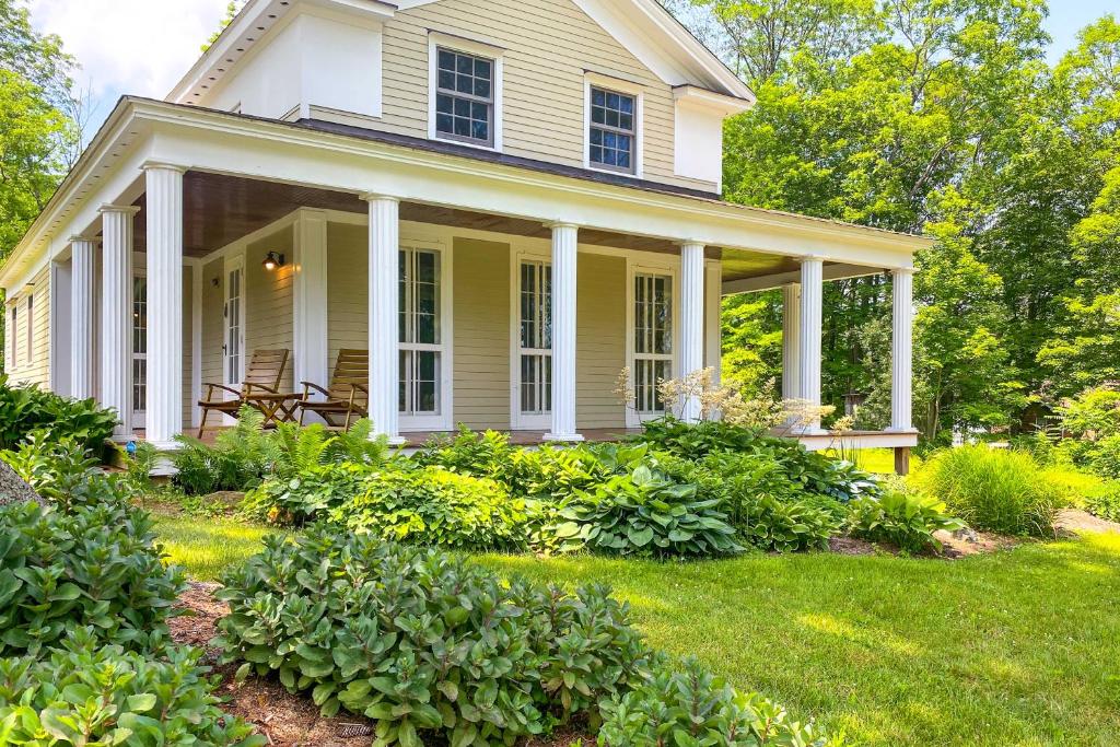 una casa blanca con porche y algunos arbustos en Charming Sharon Dwelling with Deck and Fire Pit!, en Sharon