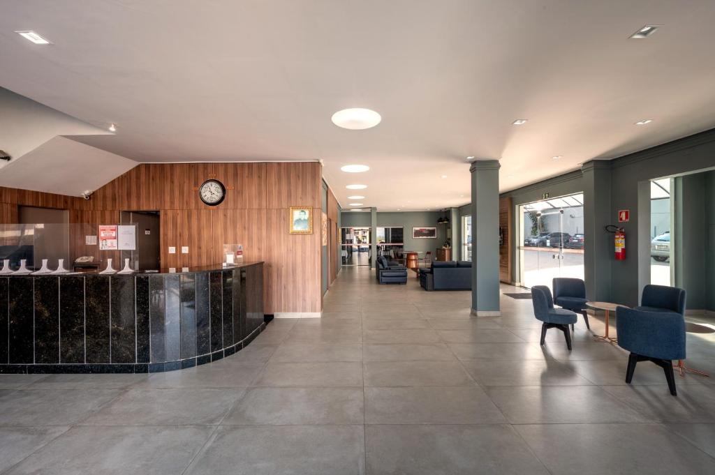a lobby with a reception desk and a clock on the wall at Italian Palace Hotel Rede Carlton in Três Corações