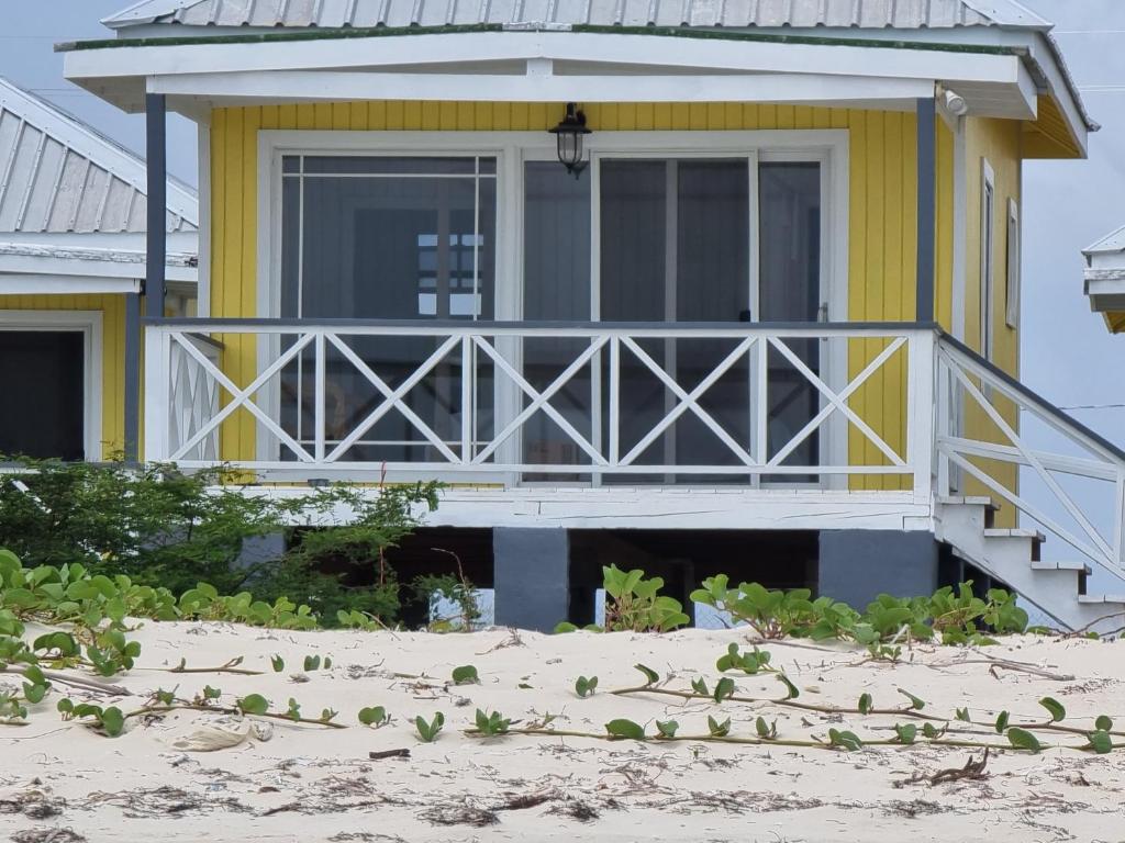 a yellow house on the beach with a porch at Harrys Cottages Cottage 5 in Codrington Village
