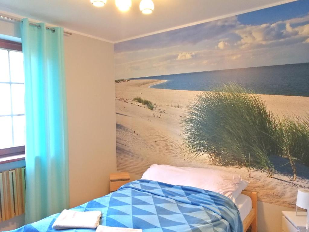 a bedroom with a painting of a beach at DOM WYPOCZYNKOWY RYBNICKA - Apartamenty in Gdynia