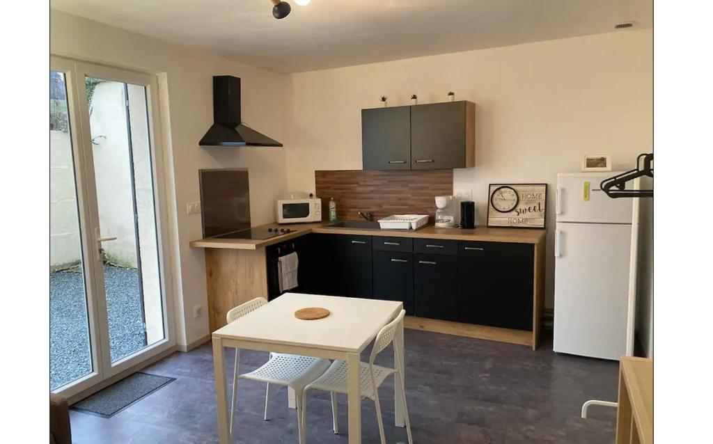 a kitchen with a table and a white refrigerator at Studio le cosy centre de gaillon(wifi) in Gaillon